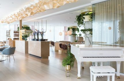 Interior of Fairmont Pacific Rim Hotel, a gay-friendly hotel. White piano, plants, and modern design. Upscale dining for gay travelers.