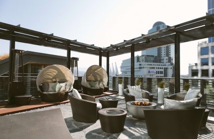 Fairmont Pacific Rim Hotel's gay-friendly rooftop patio with pod chairs, fire pit, and city views. A luxury travel experience awaits.