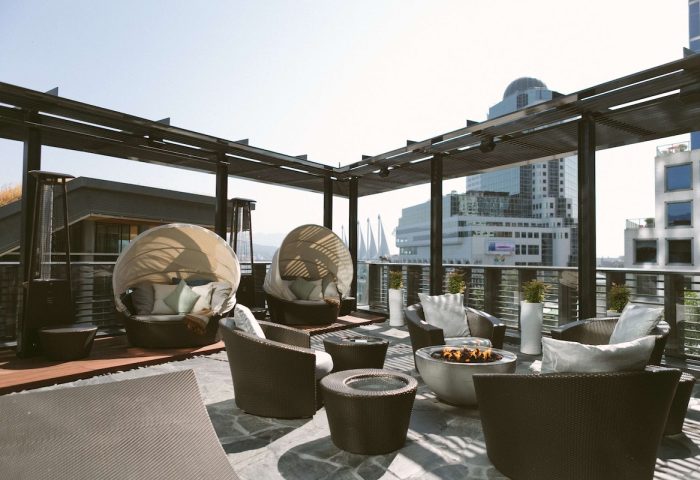 Fairmont Pacific Rim Hotel's gay-friendly rooftop patio with pod chairs, fire pit, and city views. A luxury travel experience awaits.
