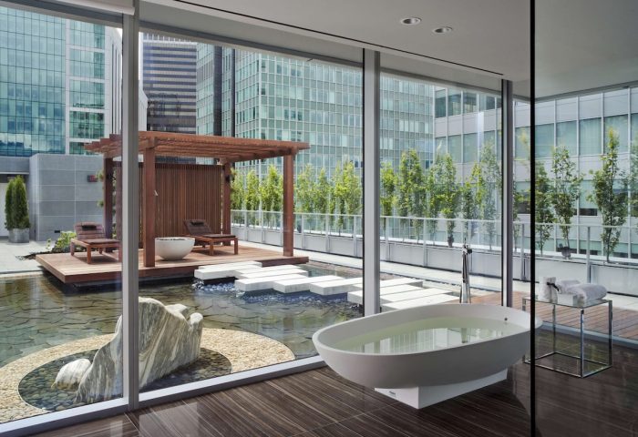 Fairmont Pacific Rim Hotel gay-friendly suite. Bathtub, pond, & lounge chairs on a patio with city views. Luxury gay travel in Vancouver.