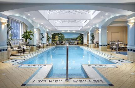 Indoor pool at the Fairmont Royal York, a gay-friendly hotel in Toronto. The pool area features lounge chairs and a mural.
