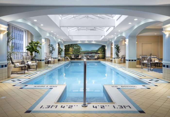 Indoor pool at the Fairmont Royal York, a gay-friendly hotel in Toronto. The pool area features lounge chairs and a mural.