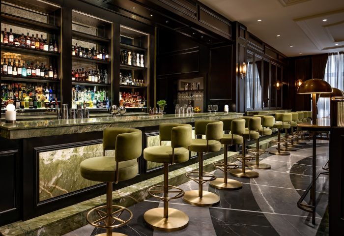 Gay-Friendly Hotel Fairmont Royal York bar. Olive green bar stools line the marble counter, bottles displayed on shelves behind.