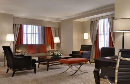 Fairmont Royal York hotel suite. Gay-friendly hotel room with sofa, chairs, desk, and orange accents. Upscale lodging for gay travelers.