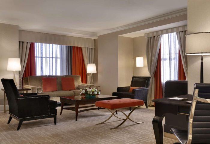 Fairmont Royal York hotel suite. Gay-friendly hotel room with sofa, chairs, desk, and orange accents. Upscale lodging for gay travelers.