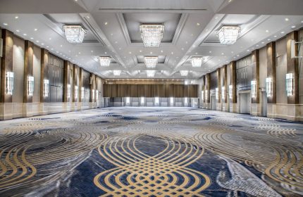 Fairmont Royal York's ballroom, a gay-friendly hotel, features a patterned carpet, chandeliers, and wall sconces, perfect for events.