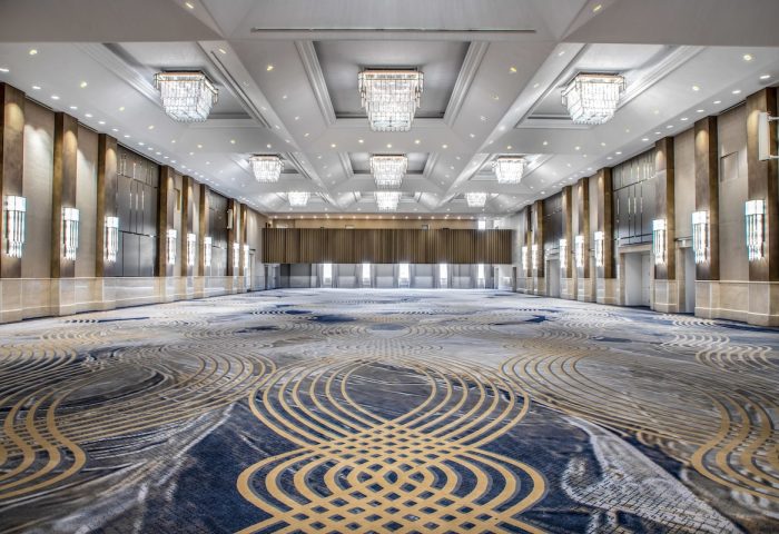 Fairmont Royal York's ballroom, a gay-friendly hotel, features a patterned carpet, chandeliers, and wall sconces, perfect for events.