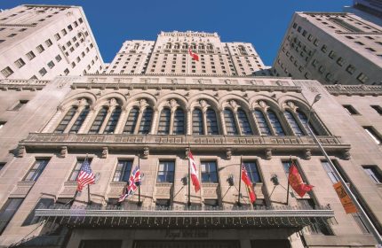 Facade of Fairmont Royal York, a gay-friendly hotel. Flags of different countries adorn the hotel's exterior. Toronto, Canada.