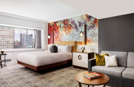 Fairmont The Queen Elizabeth Hotel room. Gay-friendly hotel with modern decor, city view, bed, and sofa. Ideal for gay men travel.