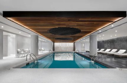Indoor pool at Fairmont The Queen Elizabeth, a gay-friendly hotel in Montreal. Loungers and seating areas surround the pool. Modern design.