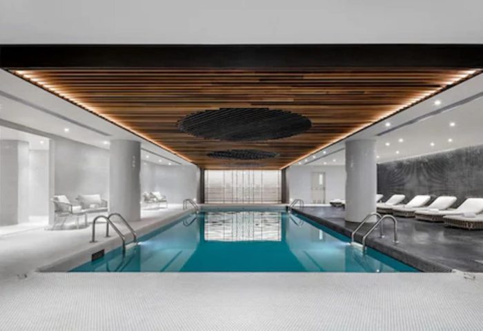 Indoor pool at Fairmont The Queen Elizabeth, a gay-friendly hotel in Montreal. Loungers and seating areas surround the pool. Modern design.