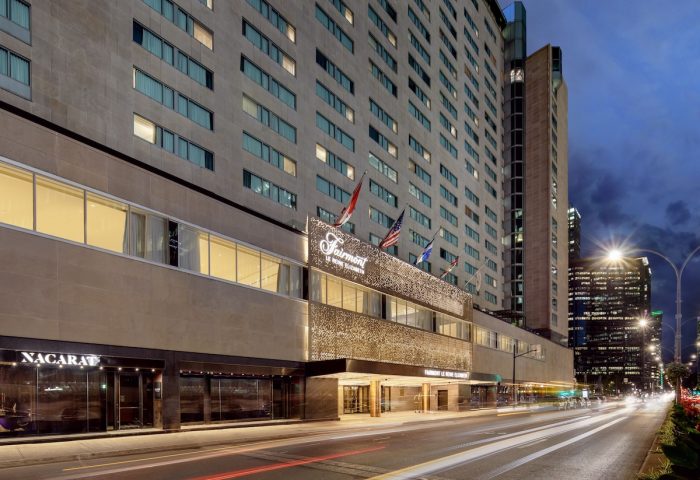 Fairmont The Queen Elizabeth, a gay-friendly hotel in Montreal. Exterior view at dusk with city lights and traffic. Upscale travel choice.