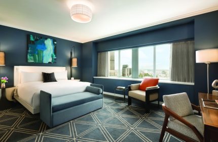 Fairmont The Queen Elizabeth hotel room. Gay-friendly hotel with a bed, chair, desk, and city view. Luxury travel for gay men.