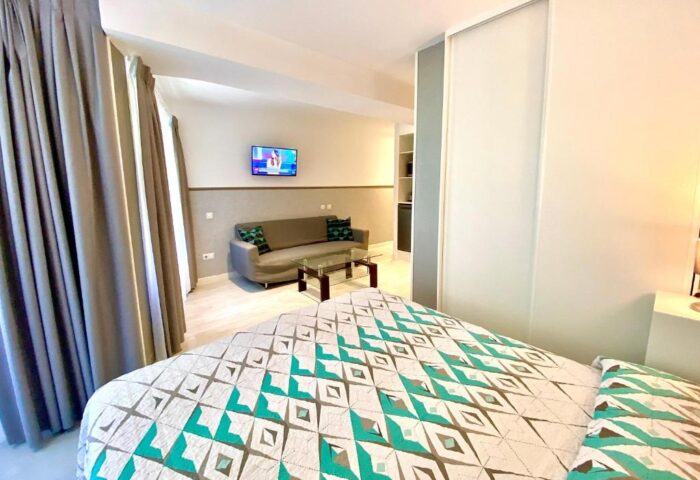 Far Home Gran Via gay-friendly hotel room. Modern design with bed, sofa, TV, and glass table. Comfortable stay for gay travelers.