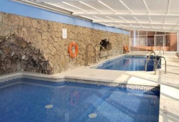 Indoor pool at Fenix Torremolinos, an adults-only, gay-friendly hotel. Recommended for gay travelers. Features blue tiled pools and stone wall.