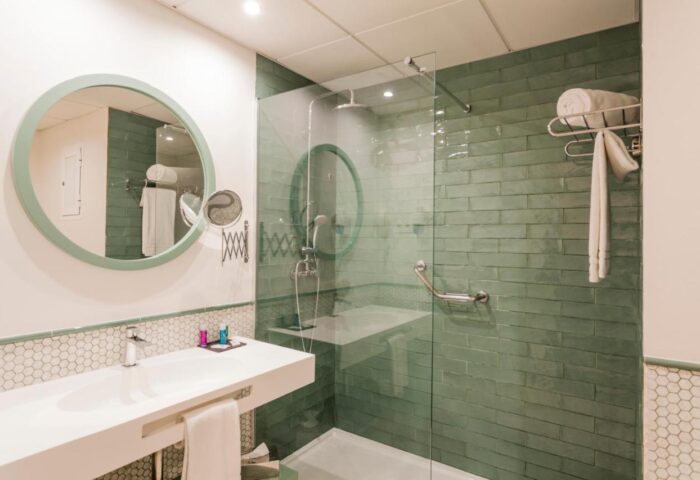Fenix Torremolinos Adults Only hotel bathroom. Modern design with green tile shower, round mirror, and white sink. Gay-friendly hotel.
