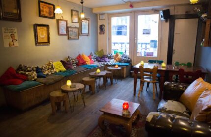 Interior of Gay-Friendly Flying Pigs Downtown Hostel in Amsterdam. Lounge area with colorful pillows, tables, and cozy seating. Relaxed vibe.