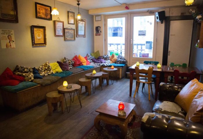 Interior of Gay-Friendly Flying Pigs Downtown Hostel in Amsterdam. Lounge area with colorful pillows, tables, and cozy seating. Relaxed vibe.