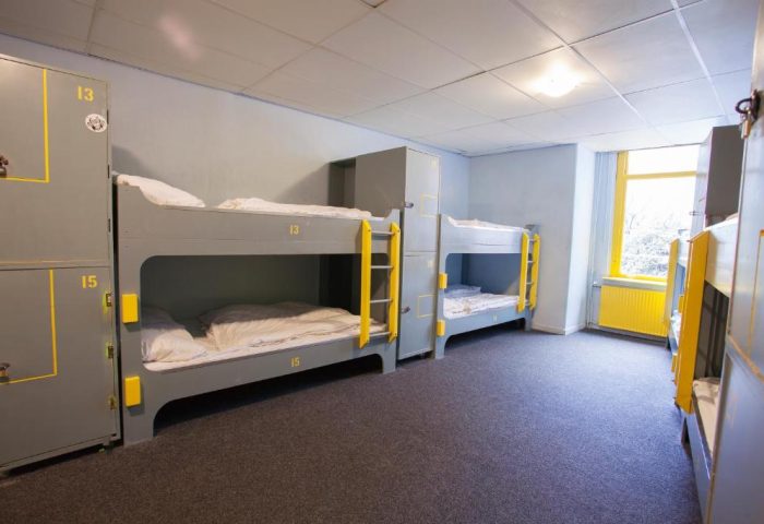 Flying Pigs Downtown Hostel Amsterdam dorm room. Bunk beds with yellow accents. Gay-friendly hotel for travelers.