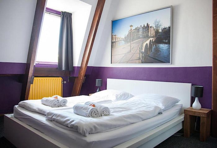 Gay-Friendly Flying Pigs Downtown Hostel Amsterdam bedroom. Double bed, Amsterdam canal print, and window. Gay travel accommodation.