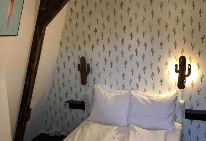 Flying Pigs Downtown Hostel Amsterdam room. Gay-friendly hotel with cactus wallpaper, wood beam, and woven light fixture.