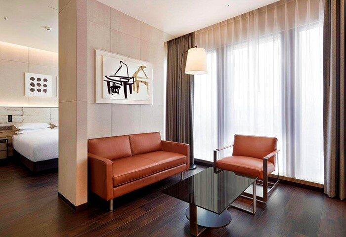 Four Points by Sheraton Seoul, Gangnam suite. Modern living room with sofa, chair, table, and art. Gay-friendly hotel room.