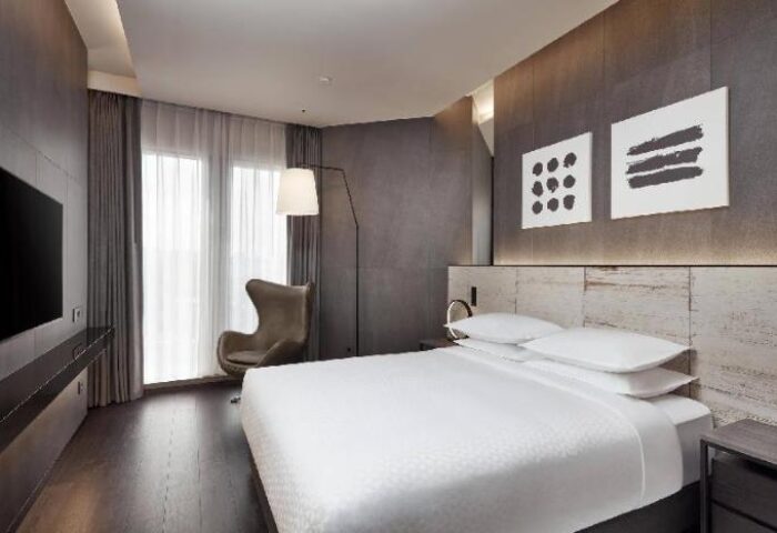 Four Points by Sheraton Seoul, Gangnam guest room. Gay-friendly hotel with modern decor, bed, chair, and TV. Comfortable stay in Seoul.