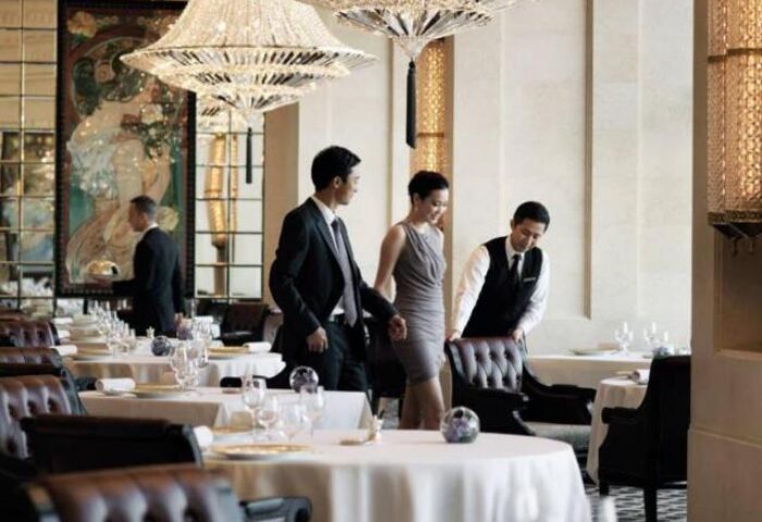 Elegant dining at the Four Seasons Hotel Hong Kong, a gay-friendly hotel. Tables set, chandeliers, and attentive service.