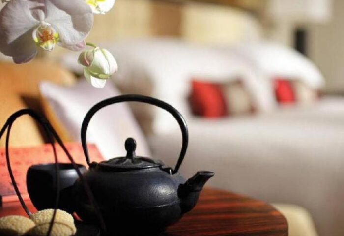 Four Seasons Hotel Hong Kong room detail: Tea set, cookies, orchid, and bed. Gay-friendly hotel for LGBT travelers.