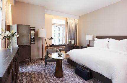 Four Seasons Hotel New York Downtown guest room. Gay-friendly hotel with luxury decor, bed, desk, and city view. Ideal for gay men travelers.