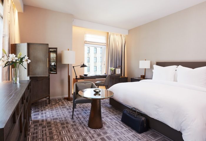 Four Seasons Hotel New York Downtown guest room. Gay-friendly hotel with luxury decor, bed, desk, and city view. Ideal for gay men travelers.