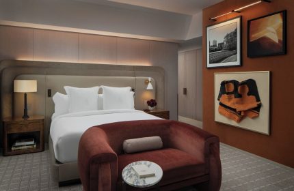 Four Seasons Hotel New York Downtown room. Gay-friendly hotel with bed, red couch, & art. Luxury lodging for gay men travelers.
