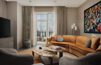 Four Seasons Hotel New York Downtown suite. Gay-friendly hotel with a living room, orange sofa, and balcony access. Upscale travel.