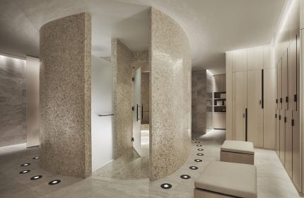 Four Seasons Hotel New York Downtown gay-friendly spa area. Modern design with mosaic walls, shower, lockers, and ambient lighting. Luxurious travel.