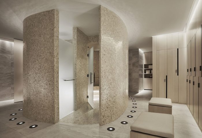 Four Seasons Hotel New York Downtown gay-friendly spa area. Modern design with mosaic walls, shower, lockers, and ambient lighting. Luxurious travel.