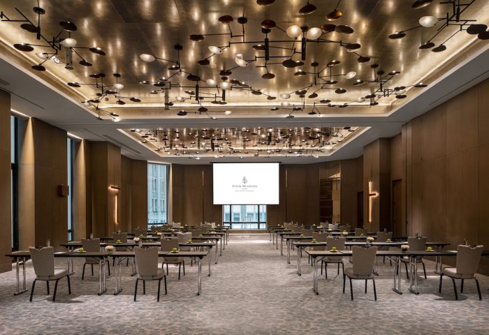 Four Seasons Hotel New York Downtown ballroom. Gay-friendly hotel with modern lighting, tables, and chairs set up for a meeting.