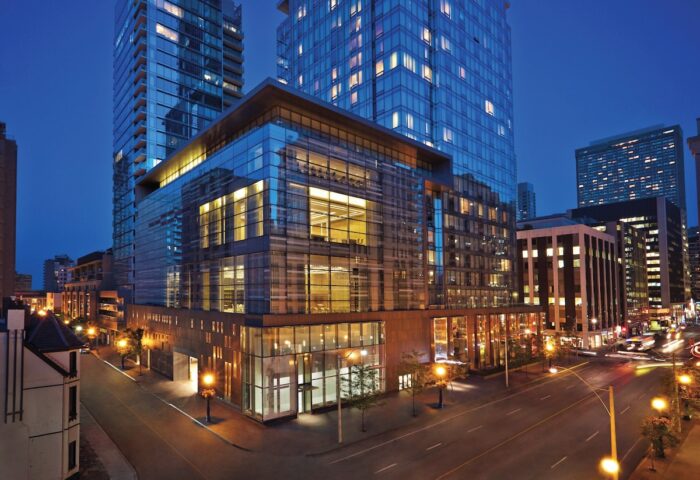 Four Seasons Hotel Toronto at Yorkville. Gay-friendly hotel exterior view at night. Modern glass architecture, street view. Luxury travel.
