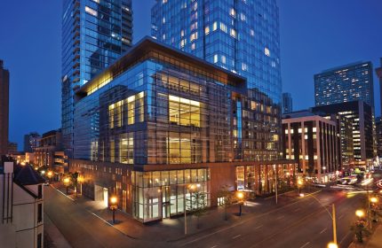 Four Seasons Hotel Toronto at Yorkville. Gay-friendly hotel exterior view at night. Modern glass architecture, street view. Luxury travel.