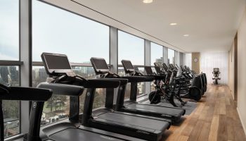 Four Seasons Hotel Toronto at Yorkville gym. Treadmills and exercise bikes line windows with city views. Gay-friendly hotel fitness center.