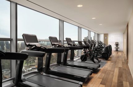 Four Seasons Hotel Toronto at Yorkville gym. Treadmills and exercise bikes line windows with city views. Gay-friendly hotel fitness center.