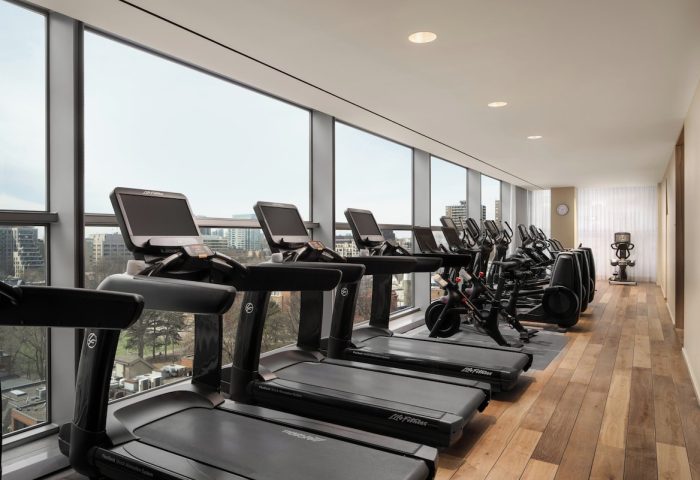Four Seasons Hotel Toronto at Yorkville gym. Treadmills and exercise bikes line windows with city views. Gay-friendly hotel fitness center.