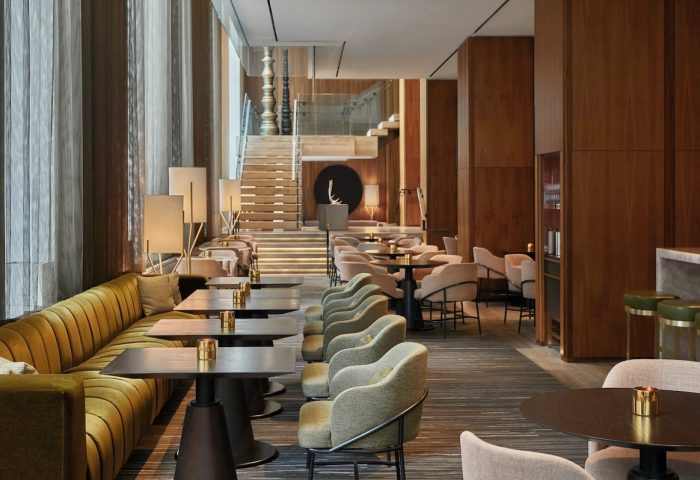 Four Seasons Hotel Toronto at Yorkville interior. Upscale lounge area with tables, chairs, and a staircase. A gay-friendly hotel.