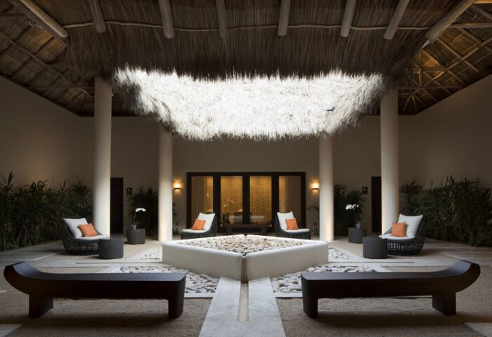Courtyard at Gay-Friendly Four Seasons Resort Punta Mita. Thatched roof, seating, & pebble fountain create a serene, luxurious ambiance.