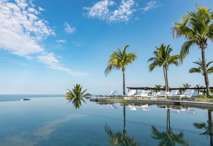 Four Seasons Resort Punta Mita: Poolside view with palm trees. Gay-friendly hotel in Punta Mita, perfect for a relaxing vacation.
