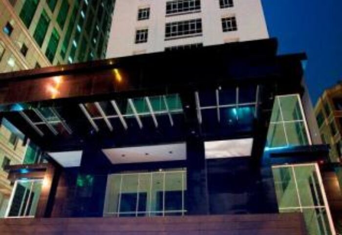 Fraser Place Kuala Lumpur entrance at night. Gay-friendly hotel with modern architecture and illuminated signage. Luxury travel destination.