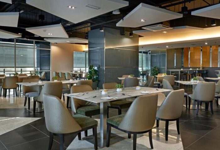 Dining area at Fraser Place Kuala Lumpur, a gay-friendly hotel. Tables with modern chairs, plants, and stylish lighting.