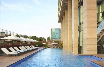 Poolside view at Fraser Residence Menteng Jakarta, a gay-friendly hotel. Lounge chairs and umbrellas offer relaxation in this urban oasis.
