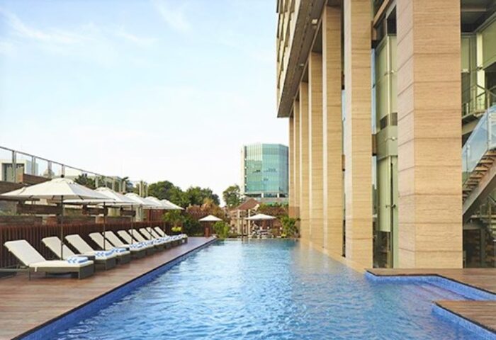 Poolside view at Fraser Residence Menteng Jakarta, a gay-friendly hotel. Lounge chairs and umbrellas offer relaxation in this urban oasis.