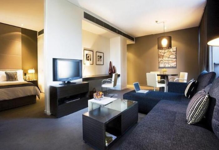 Fraser Suites Sydney gay-friendly hotel room. Modern interior with a bed, TV, sofa, dining table, and workspace. Stylish and comfortable.