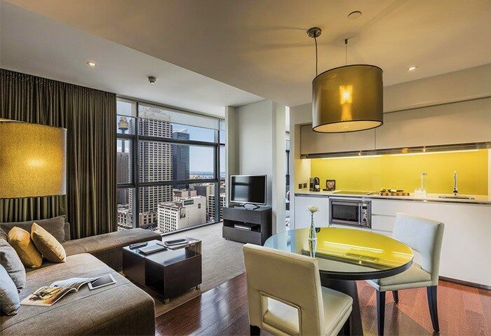 Interior of Fraser Suites Sydney, a gay-friendly hotel. Living area, kitchen, and city view. Modern design, comfortable stay for gay travelers.